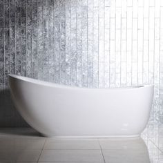 a white bathtub sitting on top of a tiled floor next to a wall mounted faucet