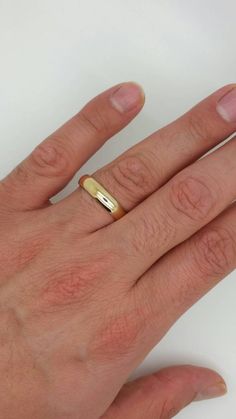 a person's hand with a gold ring on it