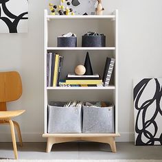 a white book shelf filled with books next to a wooden chair