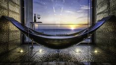 a hammock hanging in front of a window overlooking the ocean at sunset or sunrise