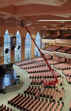 an empty auditorium with rows of seats and a red crane in the middle of the room