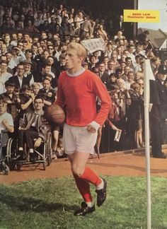 a man in red shirt and white shorts holding a basketball on field next to crowd