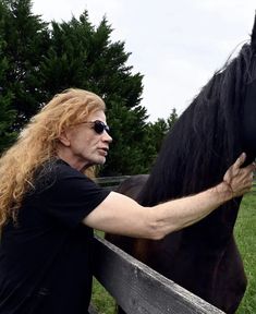 a man is petting a black horse