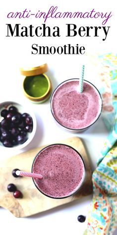 two glasses filled with berry smoothie on top of a cutting board next to blueberries