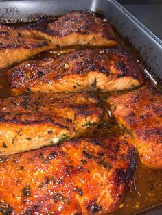 some meat is cooking in a pan with brown sauce on the bottom and green stuff on top