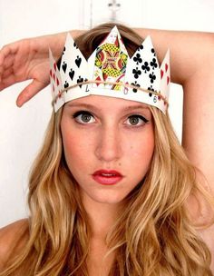 a woman with a crown on her head is posing for the camera while holding her hands behind her head