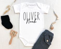 a baby's bodysuit with the words lucas and other items laid out next to it