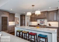 a kitchen with marble counter tops and bar stools in front of the center island