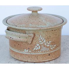 an old ceramic pot is sitting on the counter top, and it's decorated with leaves