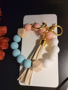 a bracelet with tassels and beads is sitting on a card next to a flower