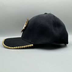 a black baseball cap with gold beading on the front and side, against a white background