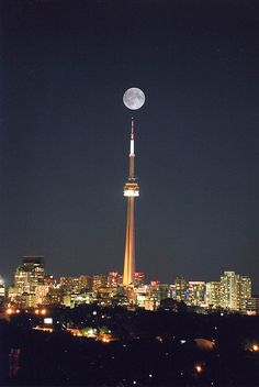 the full moon is seen in the sky over a cityscape at night with skyscrapers lit up