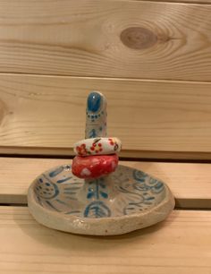 a small blue and white plate with a red object on it's top sitting on a wooden surface