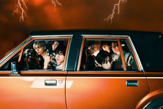 a group of people sitting in the passenger seat of a car with lightning behind them