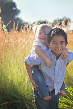 two young boys are hugging each other in the middle of a field with tall grass