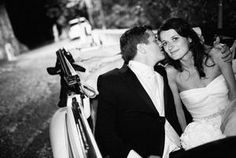 a bride and groom kissing in the back of a car on a street at night