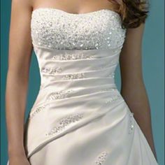 a woman in a white wedding dress with beading on the bodicet and waist