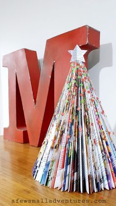 a christmas tree made out of magazines sitting on top of a wooden floor next to the letter m