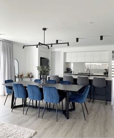 a dining room table with blue chairs and white walls