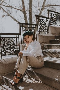 a woman is sitting on some steps and looking at the camera with her hand under her chin