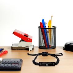 an office desk with pens, pencils and a calculator