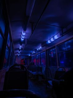 the inside of a bus at night with its lights on and people sitting in seats