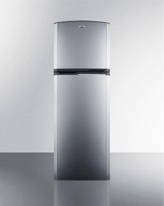 a silver refrigerator sitting on top of a table next to a white wall and floor