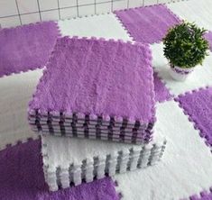 purple and white rugs on the floor with a potted plant