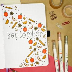 an open notebook with the word september surrounded by markers, pens and other office supplies