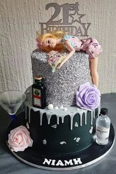 a birthday cake with a barbie doll laying on top of it and two bottles next to it