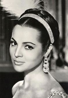 an old black and white photo of a woman wearing a tiara with feathers on it