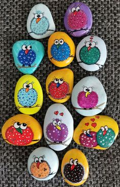 a bunch of rocks with different colored birds painted on them, sitting on a table