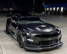 a chevrolet camaro is parked in a parking lot at night with its hood up