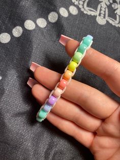 a person is holding some colorful beads in their hand and it looks like they are making a cross