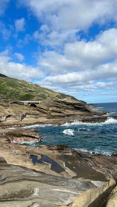 an ocean view with waves crashing on the rocks and blue sky in the back ground