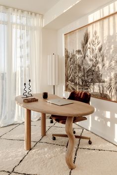 a desk with a laptop on it in front of a painting and window sill