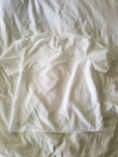 "Vintage white blouse. Made by Jonquil by Judy Bond. Crew neck. Pleated front with lace applique. Short sleeves. Button closure at nape. Boxy. 80s. 100% polyester. (measurements taken flat) Label size: 10 Bust: 21\" Waist: 20.5\" Length: 25.5\" Shoulder width: 15\" Sleeve length: 10.5\" Armscye: 10\" Excellent vintage condition. No rips, holes, or stains." White Puff Sleeve Top For Spring, White Puff Sleeve Top For Summer, White Relaxed Fit Blouse With Crew Neck, White Relaxed Short Sleeve Top For Spring, White Blouse With Relaxed Fit And Crew Neck, White Relaxed Fit Crew Neck Blouse, White Relaxed Fit Short Sleeve Top For Spring, Classic Plain Blouse For Spring, Classic Solid Short Sleeve Top For Summer