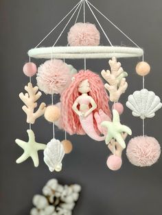 a pink and white mermaid mobile hanging from a ceiling