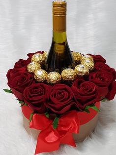 a bottle of wine and some chocolates in a box with red ribbon around it