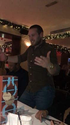 a man standing in front of a table with food and drinks on it, giving the thumbs up sign