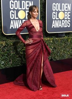 a woman in a red gown on the red carpet at an awards event with her legs slit