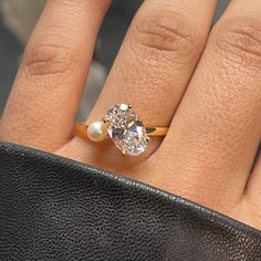 a woman's hand with a diamond and pearl ring on top of her finger