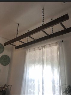 a wooden beam hanging from the ceiling in a room with white walls and curtains behind it