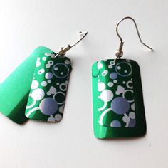 two green and white earrings on a white surface with silver ear wires hanging from them