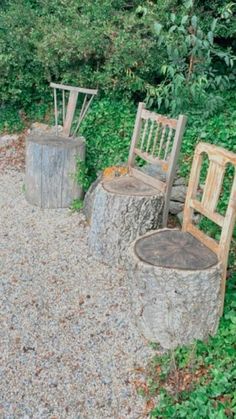 two wooden chairs sitting next to each other on top of a gravel road covered ground