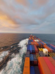 an aerial view of a large cargo ship in the middle of the ocean at sunset