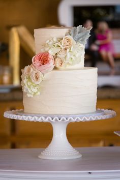 a three tiered cake with flowers on it sitting on top of a white plate