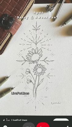 an image of a flower drawn on paper next to some pens and inking supplies