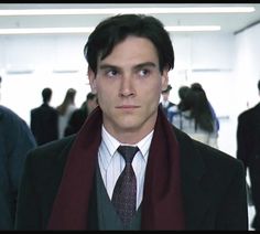 a man in a suit and tie is looking at the camera while wearing a scarf