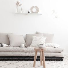 a living room with a white couch and some pillows on the floor, along with other furniture